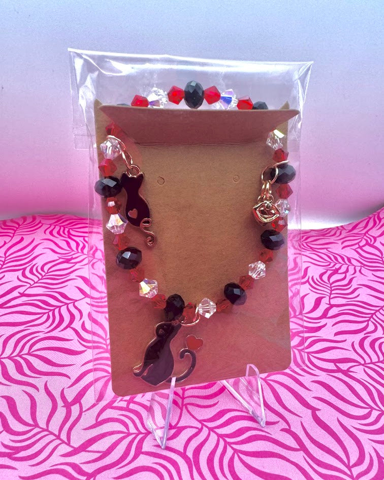 Pulsera hecha a mano con diseño de gatito rojo y negro.