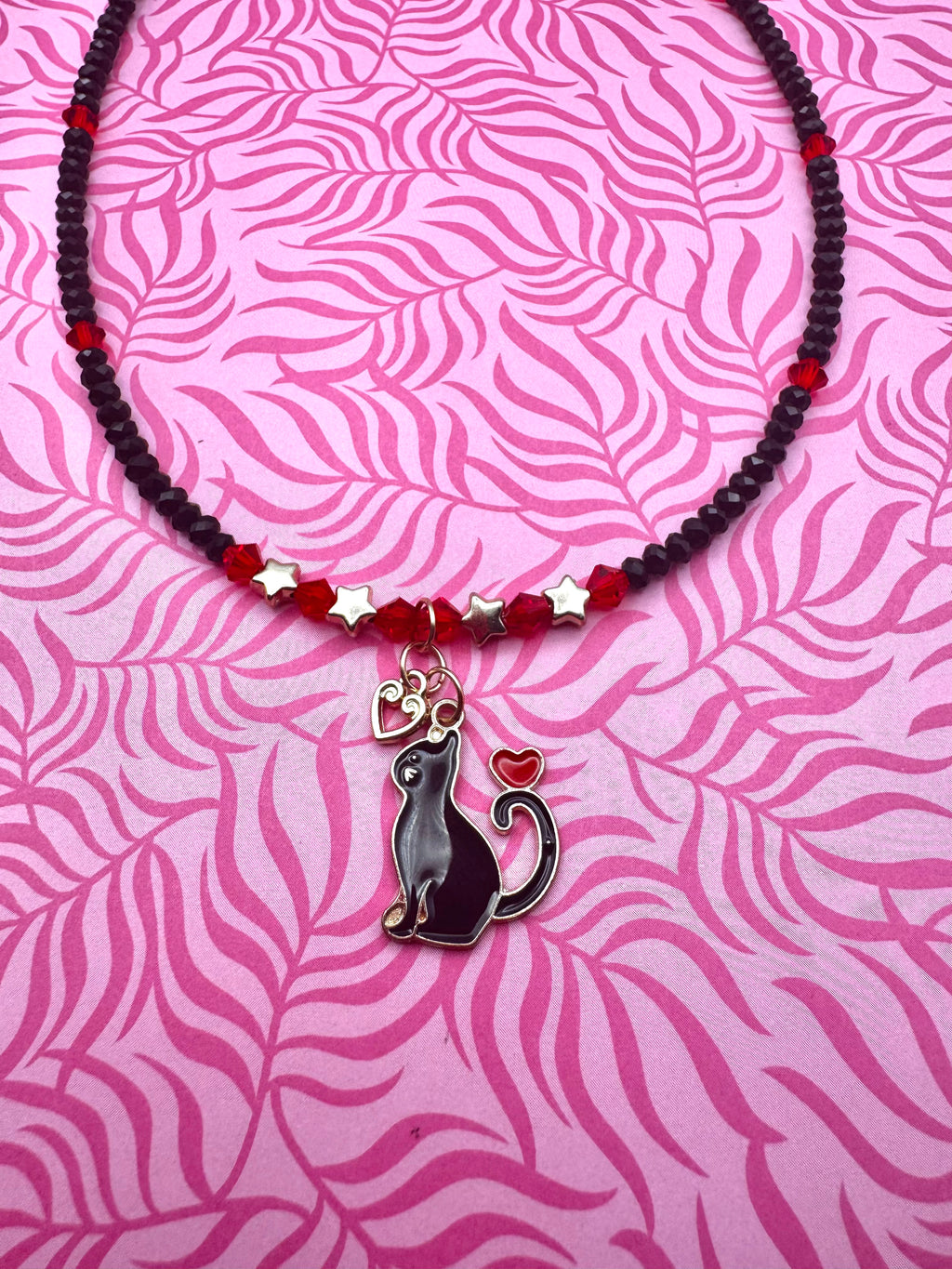 Collar hecho a mano con diseño de gatito enamorado en rojo y negro.