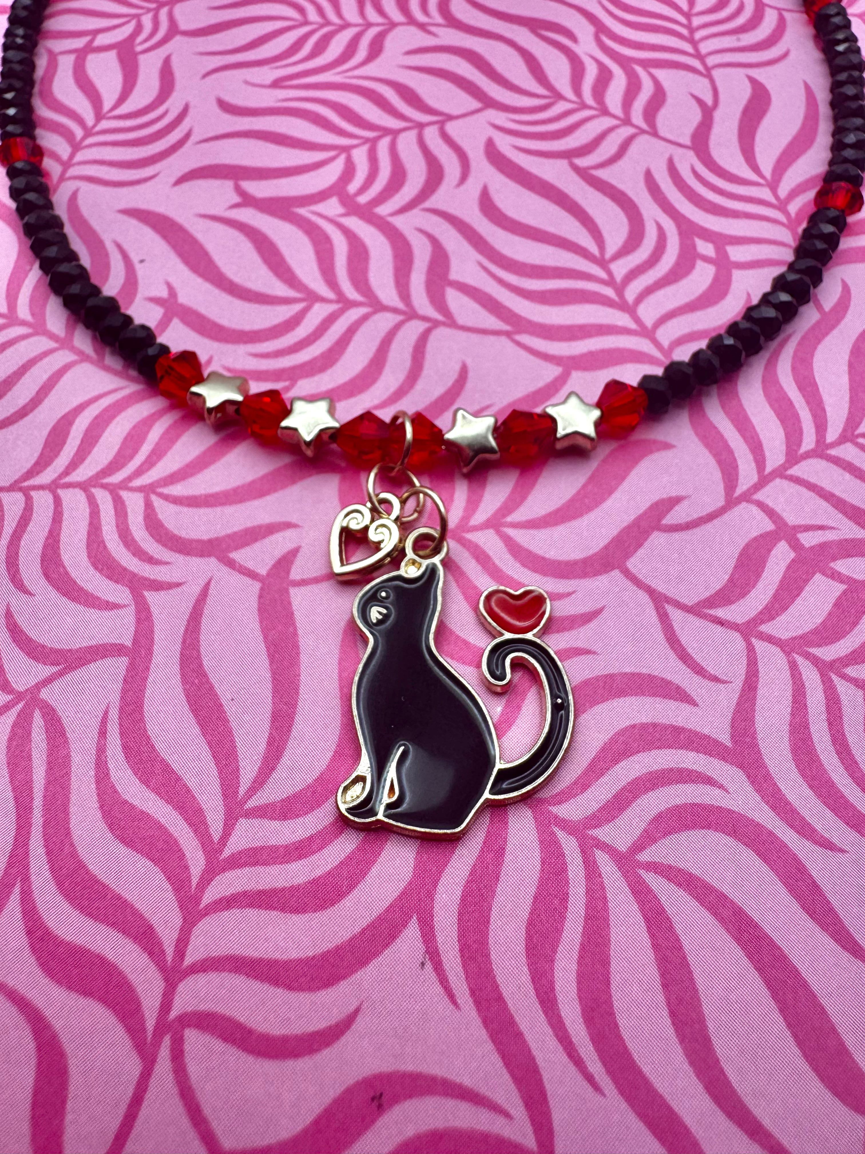 Collar hecho a mano con diseño de gatito enamorado en rojo y negro.