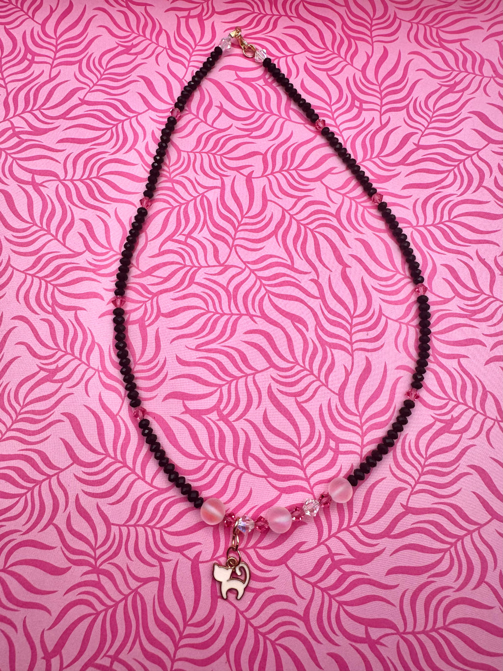 Collar hecho a mano con cuentas negras y rosas y gatito blanco.