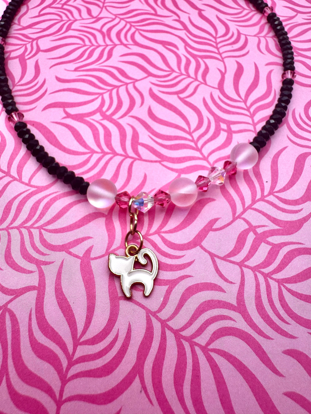 Collar hecho a mano con cuentas negras y rosas y gatito blanco.