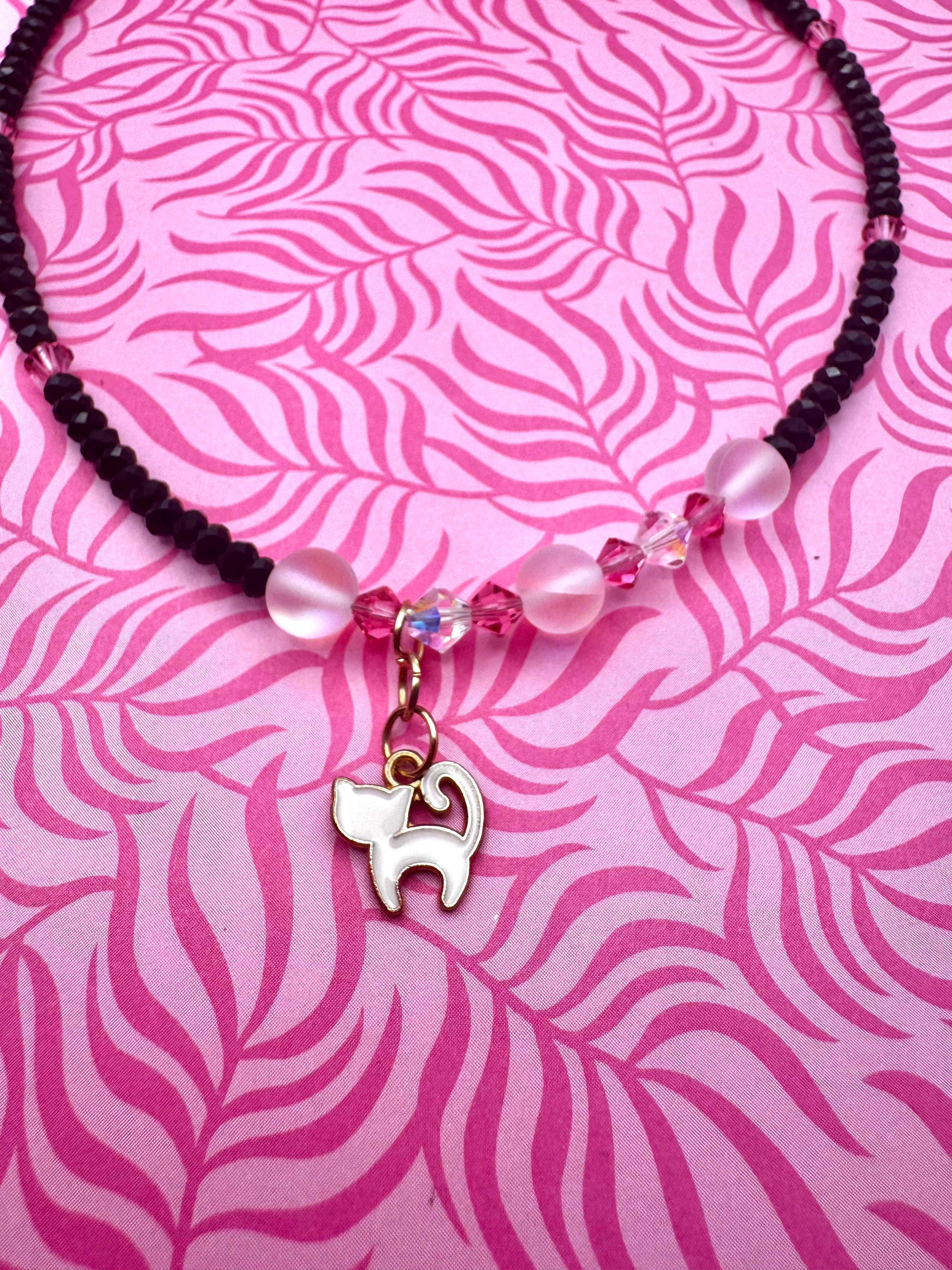Collar hecho a mano con cuentas negras y rosas y gatito blanco.